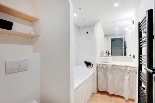 une salle de bain blanche avec une baignoire et un lavabo dans l'établissement Appartement équipé - Parking - Proche commerces, à Rosny-sous-Bois