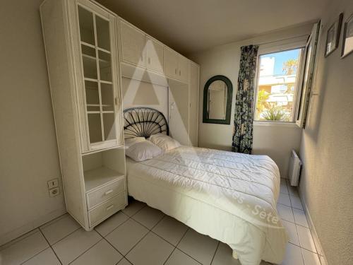 une chambre avec un lit blanc et une fenêtre dans l'établissement 1ere ligne et vue mer, T3 pour 5 personnes, à Sète