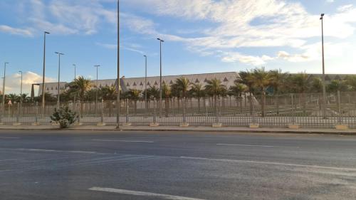 an empty street in front of a building with palm trees at Pyramids Heritage suites in Ghaţāţī