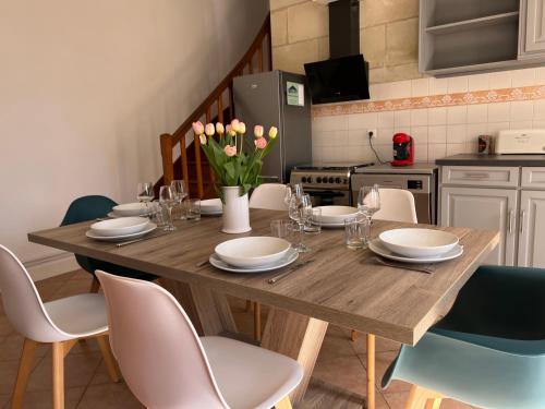une table à manger avec des chaises et une table en bois avec des fleurs dans l'établissement Chez Riton - Château de Thésée, à Thésée