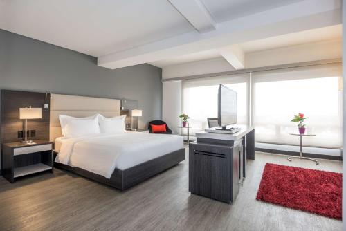 a bedroom with a bed and a desk with a mirror at NH Bogota Urban 26 Royal in Bogotá