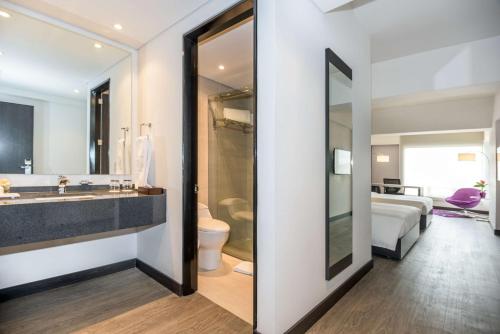 a bathroom with a sink and a toilet and a bed at NH Bogota Urban 26 Royal in Bogotá