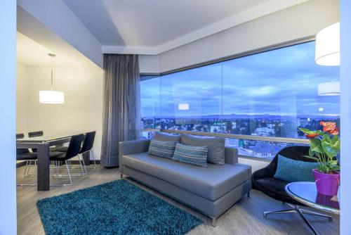 a living room with a couch and a table with a view at NH Bogota Urban 26 Royal in Bogotá