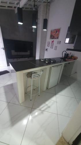 a kitchen with a counter and a stool in a room at Pousada chc in Praia Grande