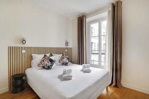 une chambre avec un grand lit blanc et une fenêtre dans l'établissement Pick A Flat's Apartments in Madeleine - Rue Tronchet, à Paris