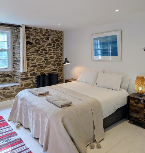a bedroom with a bed and a stone wall at Ramble & Rye - The Nest in Talland