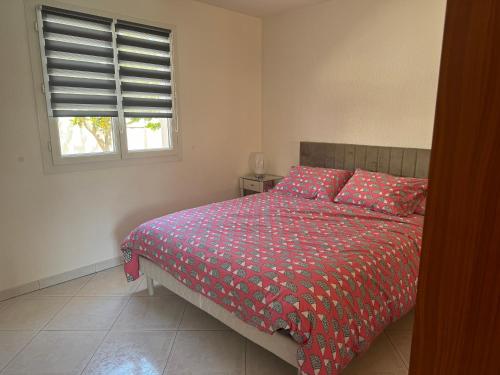 une chambre avec un lit avec une couette rouge et une fenêtre dans l'établissement la Villa Bella Vista, à Agde
