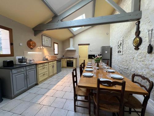 une grande cuisine avec une grande table en bois et des chaises dans l'établissement La Closerie – Château de Thésée, à Thésée