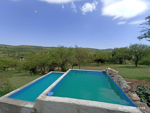 an empty swimming pool in a field with trees at vistas del valle casa amarilla in Valle Hermoso