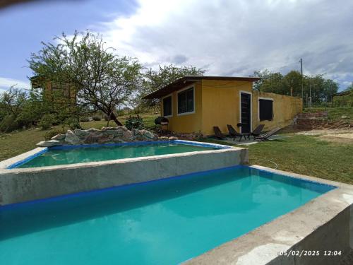 a house with a swimming pool in front of a house at vistas del valle casa amarilla in Valle Hermoso