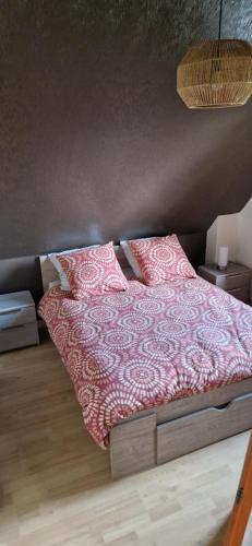 a bedroom with a bed with pink sheets and pillows at Maison de Cathy et Jean-Louis in Brumath