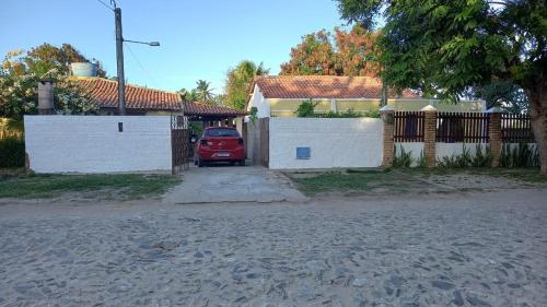 a red car parked in front of a house at Casa de Praia em Parajuru in Beberibe