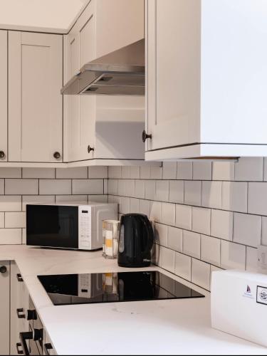 a kitchen with white cabinets and a microwave at The Bakers House in Elie