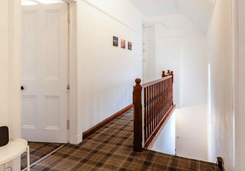a hallway with a staircase and a white door at The Bakers House in Elie