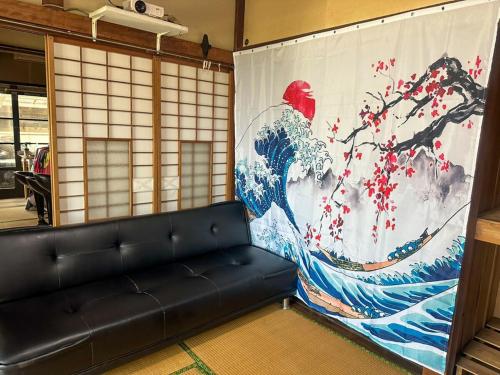 a living room with a couch and a large painting at 窓際から海と鉄道が見える宿 サウナ プロジェクター カラオケ完備 トリックマーメイド in Ito
