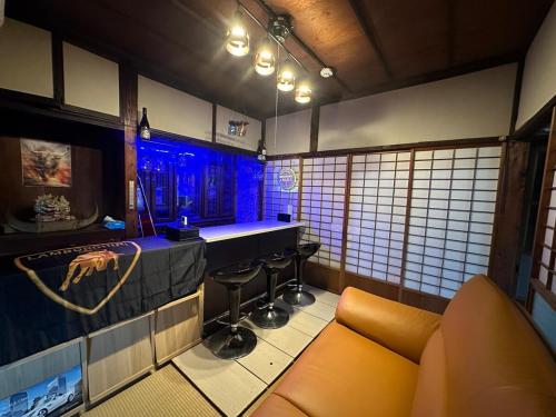 a bar with a couch andools in a room at 窓際から海と鉄道が見える宿 サウナ プロジェクター カラオケ完備 トリックマーメイド in Ito