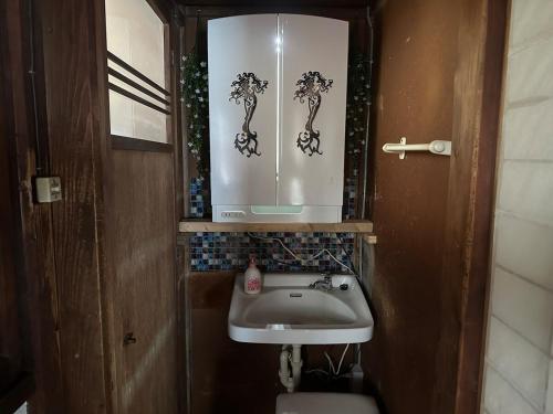 a small bathroom with a sink and a mirror at 窓際から海と鉄道が見える宿 サウナ プロジェクター カラオケ完備 トリックマーメイド in Ito