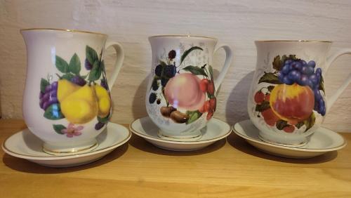 three cups and saucers with fruit on them on a table at Hainich-Zeit in Eigenrieden