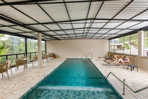 a swimming pool with two people sitting on chairs next to it at Vila Europeia Hotel in Serra Negra