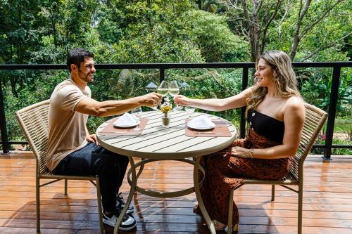 a man and woman sitting at a table with wine glasses at Vila Europeia Hotel in Serra Negra