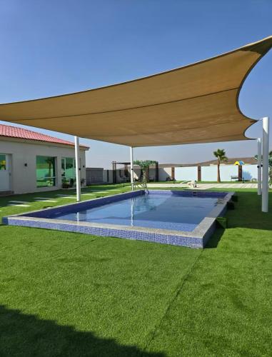 a swimming pool in a yard with a large umbrella at Valley View farm in Maghribīyah