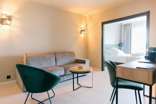 a living room with a couch and a table and chairs at Hôtel Spa Restaurant La Madrague in Lucciana