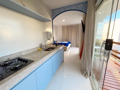 a kitchen with a sink and a room with a bed at Loft Santorini com hidro aquecida - Arraial do Cabo in Arraial do Cabo