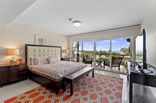 a bedroom with a bed and a television and a balcony at Beachfront - Eagle Beach - Sapphire 2BR condo E322 in Palm-Eagle Beach