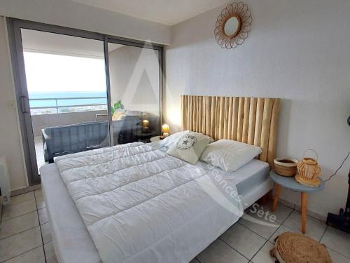 une chambre avec un grand lit et une grande fenêtre dans l'établissement T3 avec grande terrasse et vue panoramique sur la mer, à Sète