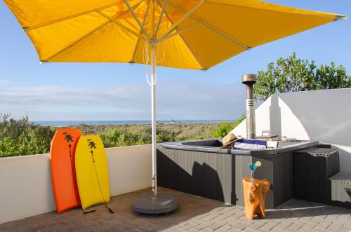 an umbrella and surfboards sitting on a patio at Bella La Vita Beachfront Villa in Velddrif