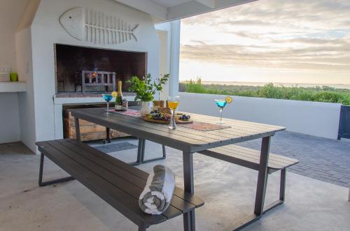 a table and bench in a room with a fireplace at Bella La Vita Beachfront Villa in Velddrif