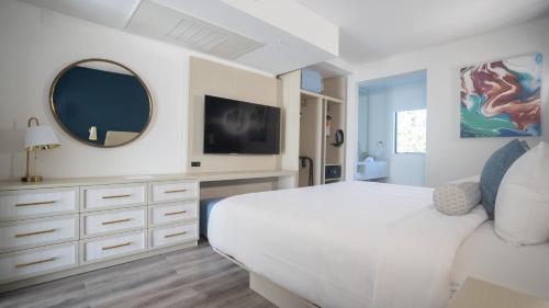 a white bedroom with a large bed and a mirror at DASKK Orlando Hotel near Universal Blvd, an Ascend Collection Hotel in Orlando