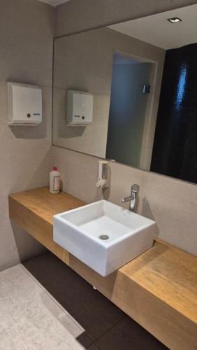 Un baño con un lavabo blanco y un espejo. en Panoramico Hollywood Palermo, en Buenos Aires