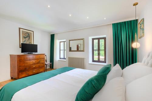 a bedroom with a large white bed with green curtains at Villa Mulino Old Mill in Črnica