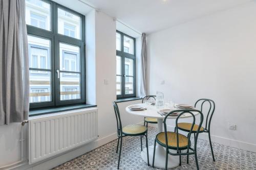 une salle à manger avec une table, des chaises et des fenêtres dans l'établissement Lille Hypercentre appartement 2 chambres, à Lille