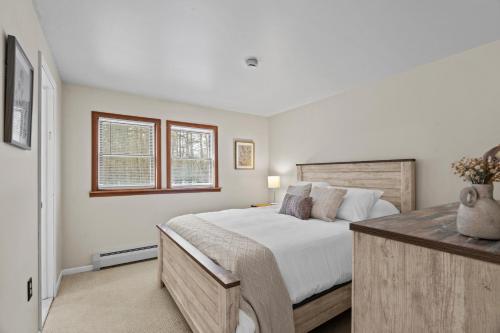 a bedroom with a large bed and two windows at 3BR Lake Luzerne Retreat with Game Room & Hot Tub in Lake Luzerne
