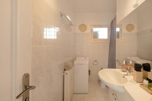 La salle de bains blanche est pourvue d'un lavabo et d'une baignoire. dans l'établissement Cosy appartement proche mer, à Antibes