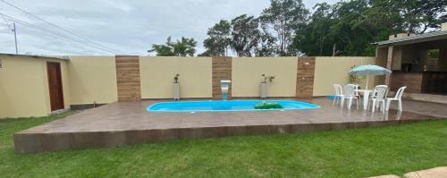 a swimming pool with chairs and a table and an umbrella at Casa de temporada SONHO DE ALTER in Alter do Chao
