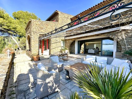 - un patio avec des meubles blancs dans un bâtiment en briques dans l'établissement Villa Serena climatisée pour 8 personnes avec piscine privée et vue mer à Carqueiranne, à Carqueiranne