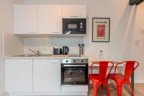 - une cuisine avec deux chaises rouges et une cuisinière dans l'établissement Studio sous les combles côté cour, parking gratuit, à Villeneuve d'Ascq
