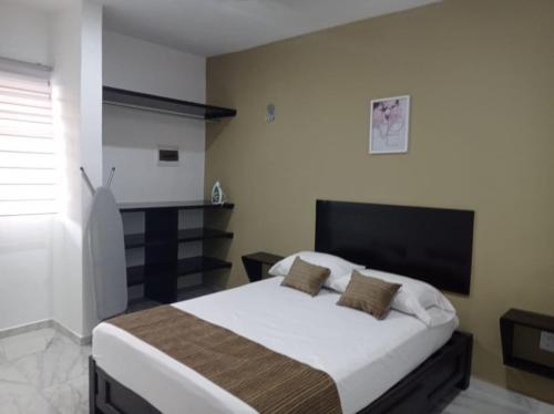 a bedroom with a bed with white sheets and brown pillows at Oasis suites Departamento5 planta alta in Campeche