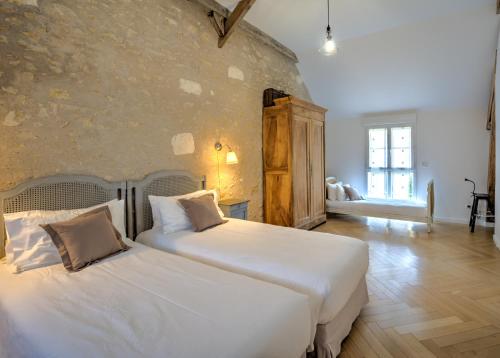 a bedroom with two beds and a stone wall at La Poulinière 4* du Domaine des Cyclamens in Verneuil-sur-Indre