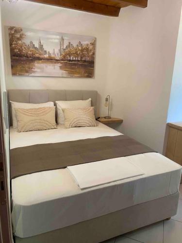 a bed in a bedroom with a painting on the wall at Modern Loft at Kalogria Beach in Stoupa