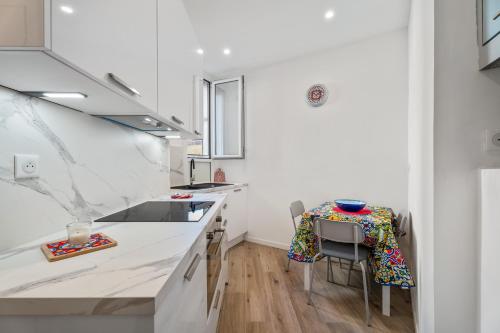 une cuisine avec des comptoirs blancs, une table et des chaises dans l'établissement Nice Renting - HONORE - Elegant apartment near Promenade des Anglais, à Nice