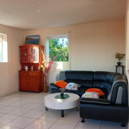 a living room with a black leather couch and a table at Charmante maison de vacances avec vue sur la mer à Le Gosier in Le Gosier
