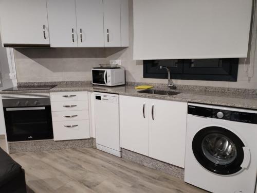 a kitchen with white cabinets and a microwave and a dishwasher at Castralvo Suites in Teruel