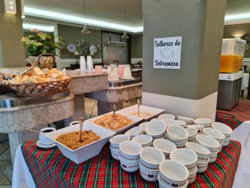 a table with bowls of food sitting on a table at Hotel Mantovani in Águas de Lindóia