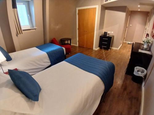 a hotel room with two beds with blue pillows at The Royal Hotel Cardiff in Cardiff