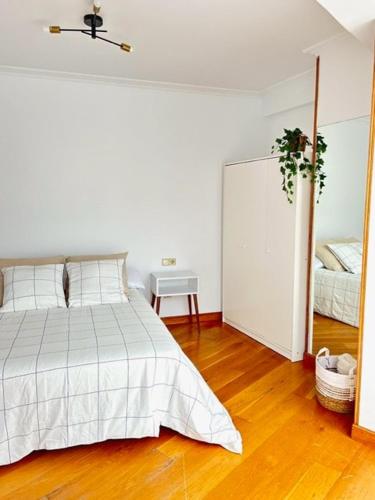 a white bedroom with a bed and a mirror at Apartamento centro Santander in Santander