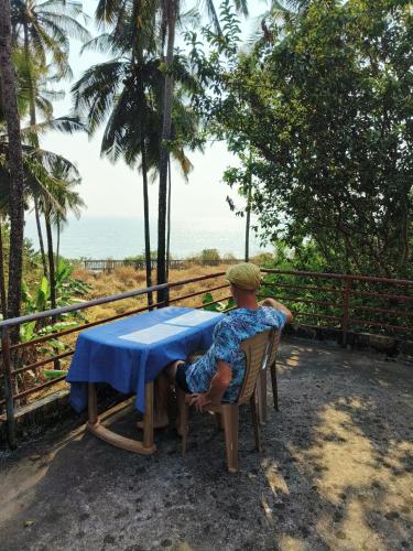 a man sitting at a table in front of the ocean at Perch Next door in Kannur